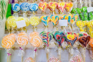 Canlı renkli şeker lolipopları grubu, bireysel plastik ambalajlı ve seçici odaklı bir şekerci dükkanında satışa sunuldu