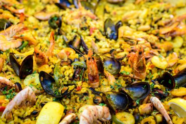 Geleneksel İspanyol paella yemeğinin büyük bir kısmını kapatıyoruz. Bir sokak yemeği festivalinde deniz ürünleri, yan görüş ve seçici bir odak noktasında deniz ürünleri ve makarna ile kızartılıyor.