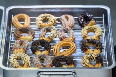 Süslü churros, geleneksel İspanyol çörekleri, şekerle süslenmiş, çikolata serpiştirilmiş, sokak yiyecekleri pazarında satılık, yumuşak odaklı.