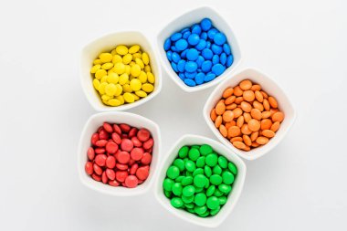 Küçük kırmızı, sarı, mavi, yeşil ve turuncu kaplamalı beş kare kase beyaz arka planda izole edilmiş M & M kareye benzer çikolata.