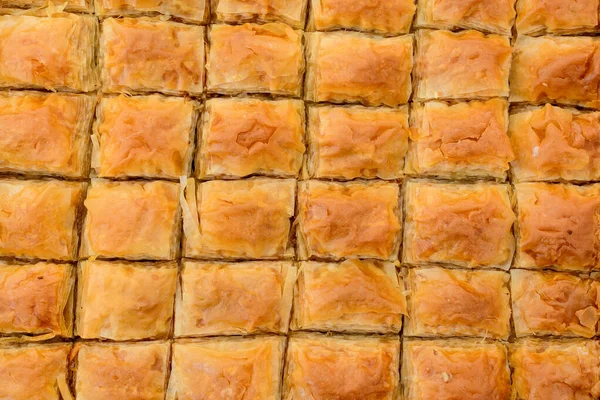 Close up of traditional oriental sweet pastry cookies known as backlava, Turkish desert with sugar, honey, walnuts and pistachio, in display at an weekend street food market, top view, soft focus