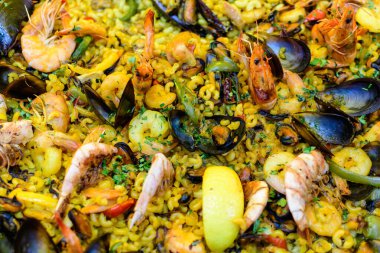 Geleneksel İspanyol paella yemeğinin büyük bir kısmını kapatıyoruz. Bir sokak yemeği festivalinde deniz ürünleri, yan görüş ve seçici bir odak noktasında deniz ürünleri ve pilav ile kızartılıyor.