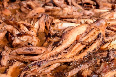 Ahtapot, geleneksel siyah bir tavada domates sosuyla pişirilmiş. Bir sokak yemeği festivalinde, deniz ürünleri yemeye hazır.