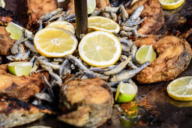 Sağlıklı deniz ürünleri yemeye hazır, bir sokak yemeği festivalinde büyük bir tavada sarı limon dilimleriyle süslenmiş büyük porsiyon kızarmış balığı kapat.