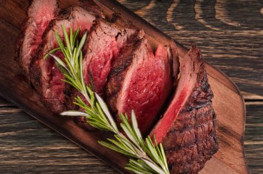 Biberiyeli ahşap bir tahtanın üzerinde sulu bir et parçası..