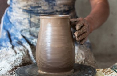 Çömlek çarkında çamurdan yapılmış Potter elleri. Potter çömlek tekeri çömleğinde yapar..