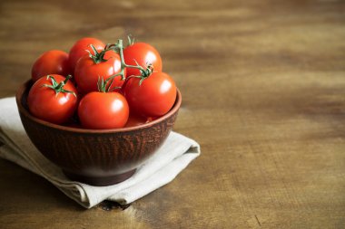 Tahta kahverengi arka planda kahverengi bir kasede taze taze kiraz domatesleri. Boşluğu kopyala.