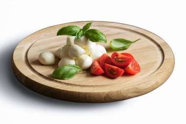 Beyaz arka planda Caprese salatası. Mozzarella peyniri, domates, fesleğen tahtada.