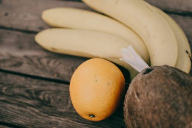 Ahşap arka planda tropik meyve. Meyve arka planı. Tahta bir masada hindistan cevizi, portakal ve muz.