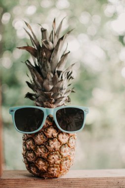Eski ahşap bir masada, gözlüklü olgun ananas, gözlüklü ananas