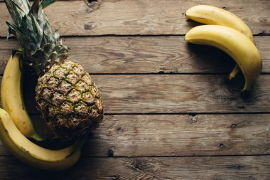 Ahşap zeminde sarı muz ve ananas. Cope alanı. Meyve arkaplanı.