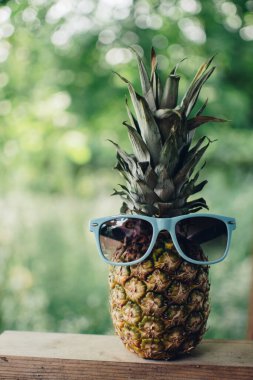 Eski ahşap bir masada, gözlüklü olgun ananas, gözlüklü ananas