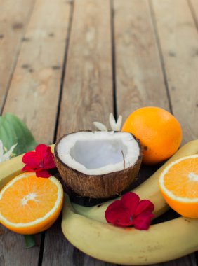 Ahşap arka planda tropik meyve. Meyve arka planı. Tahta bir masada hindistan cevizi, portakal ve muz.