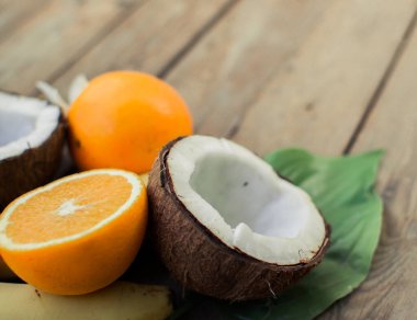 Ahşap arka planda tropik meyve. Meyve arka planı. Tahta bir masada hindistan cevizi ve portakallar.