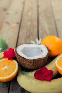 Ahşap arka planda tropik meyve. Meyve arka planı. Tahta bir masada hindistan cevizi, portakal ve muz.