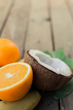 Ahşap arka planda tropik meyve. Meyve arka planı. Tahta bir masada hindistan cevizi ve portakallar.