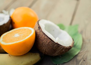 Ahşap arka planda tropik meyve. Meyve arka planı. Tahta bir masada hindistan cevizi ve portakallar.