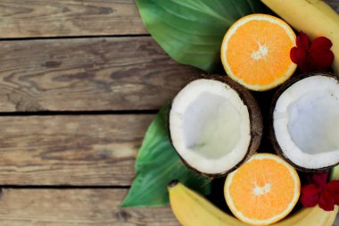 Ahşap arka planda tropik meyve. Meyve arka planı. Tahta bir masada hindistan cevizi, portakal ve muz.