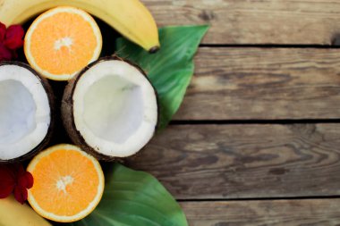 Ahşap arka planda tropik meyve. Meyve arka planı. Tahta bir masada hindistan cevizi, portakal ve muz.