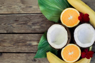 Ahşap arka planda tropik meyve. Meyve arka planı. Tahta bir masada hindistan cevizi, portakal ve muz.