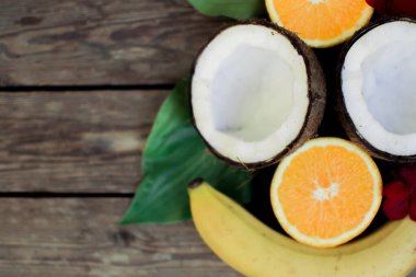 Ahşap arka planda tropik meyve. Meyve arka planı. Tahta bir masada hindistan cevizi, portakal ve muz.