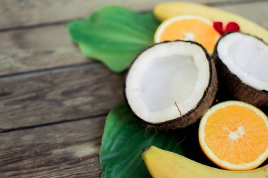 Ahşap arka planda tropik meyve. Meyve arka planı. Tahta bir masada hindistan cevizi, portakal ve muz.