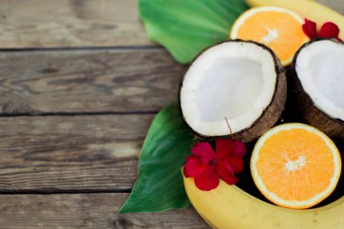 Ahşap arka planda tropik meyve. Meyve arka planı. Tahta bir masada hindistan cevizi, portakal ve muz.