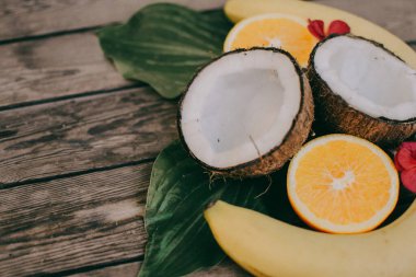 Ahşap arka planda tropik meyve. Meyve arka planı. Tahta bir masada hindistan cevizi, portakal ve muz.
