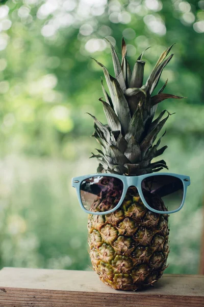 Eski ahşap bir masada, gözlüklü olgun ananas, gözlüklü ananas