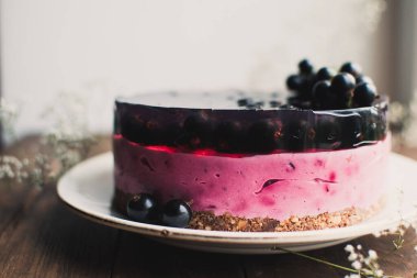 Siyah üzümlü peynirli kremalı kek. Tahta bir masada meyveli lezzetli bir pasta..