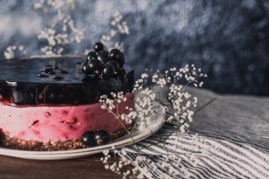 Siyah üzümlü peynirli kremalı kek. Tahta bir masada meyveli lezzetli bir pasta..