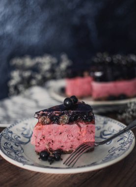 Siyah üzümlü peynirli kremalı kek. Tahta bir masada meyveli lezzetli bir pasta..