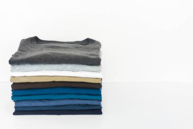 Beyaz arkaplanda bir yığın tişört, boşluğu kopyala