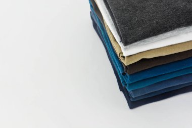 Beyaz arkaplanda bir yığın tişört, boşluğu kopyala