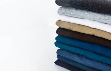 Beyaz arkaplanda bir yığın tişört, boşluğu kopyala