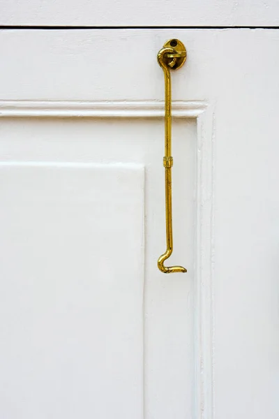 白木製の窓枠の背景に吊るされたヴィンテージゴールドカラーウィンドウフックまたは真鍮シャッターフックの閉まり コピースペース — ストック写真