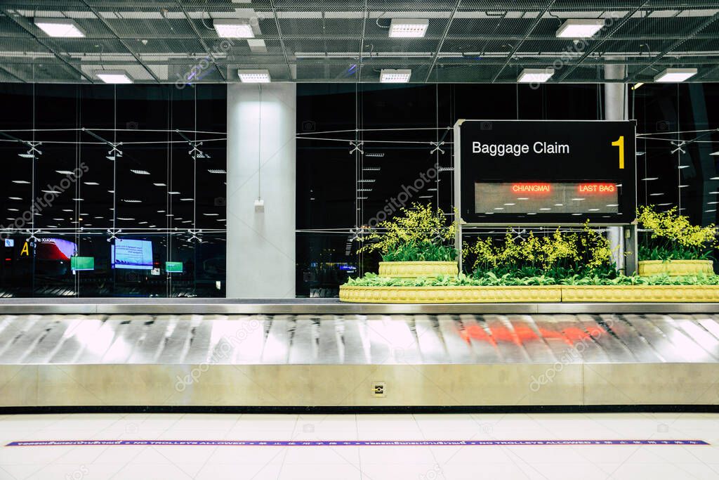 empty metal conveyor belt with baggage claim sign in arrival hall area at the modern airport