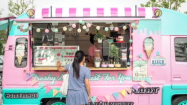 Caddelerdeki yemek festivalinde güzel pastel renkli yemek kamyonundan ev yapımı yoğurt, dondurma ve tatlı alan genç kadınların soyut ve bulanık arkaplanı