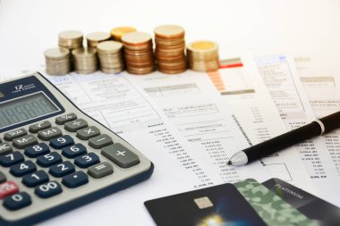 Kredi kartı ekstreleri, kalem, bozuk para yığını ve hesap makinesiyle beyaz arka plan, finansal konsept, seçici odaklanma