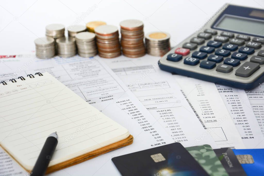close up of a credit cards with credit card statements, pen, notebook, stack of coins and calculator on white background, financial concept, copy space, selective focus