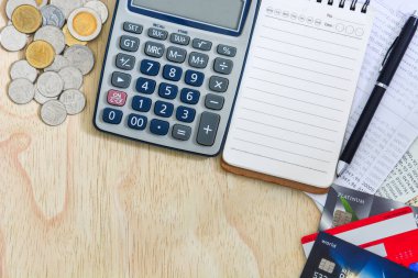 Kredi kartlarının üst görünümü, hesap defterleri tasarruf hesabı, hesap makinesi, tahta zemin üzerinde kalem ve bozuk para yığını olan not defteri, kopyalama alanı, kişisel finansal planlama kavramı