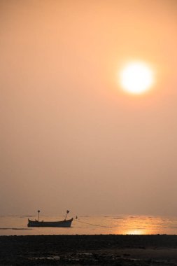 Gün batımında denizde yüzen bir tekne.