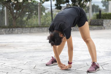 Parktaki fitness antrenmanından önce genç bayan antrenmanı. Sağlıklı genç bir kadın dışarıda ısınıyor..