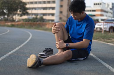 Koşudan sonra yaralanan koşucu. Acı veren bacağa dokunuyor..