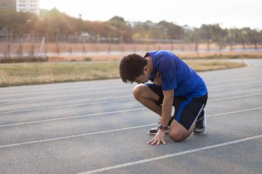 Adam koşu pistinde çok koştuktan sonra yoruldu. Kalp bölgesine dokunuyor..