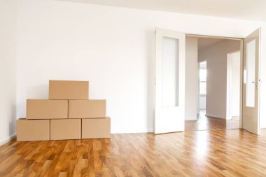 Moving Boxes In An Empty Apartment Against A White Wall clipart