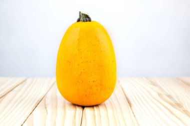 Dekoratif bir balkabağı (spagetti kabağı) tahtada duruyor ve arka planda bir metin var.