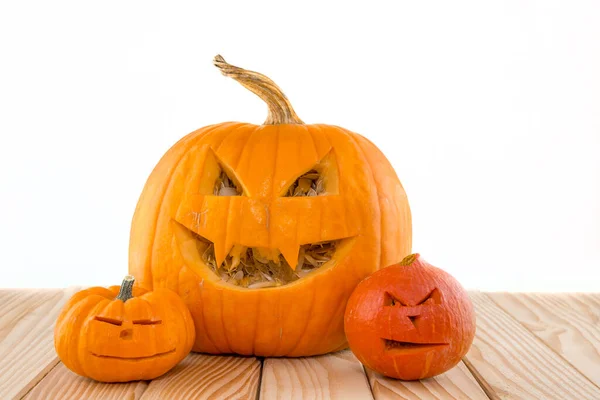 Three pumpkins with face lying on wooden boards