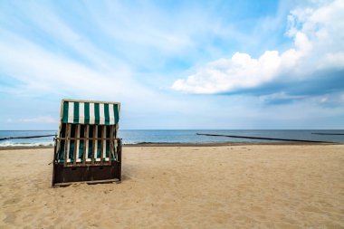 Denizin kenarında kumsalda boş bir plaj sandalyesi duruyor.