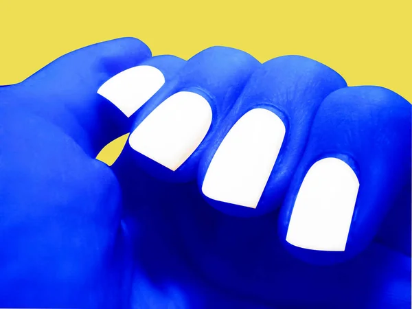 Blue hand with white nails on yellow background. Manicure.